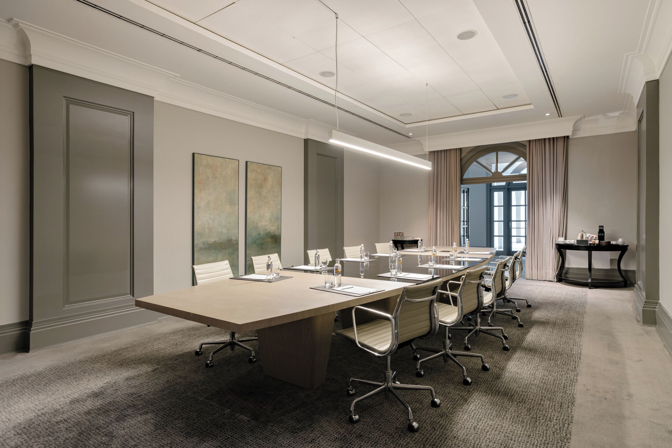 A conference room with a long table, chairs, and a small table with a laptop.