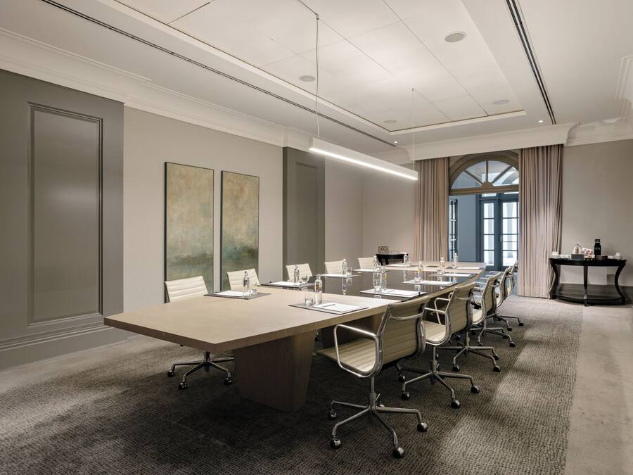 A conference room with a long table, chairs, and a small table with a laptop.