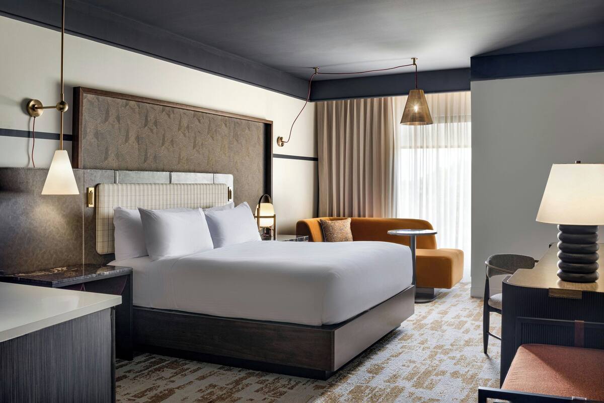 Una habitación de hotel moderna con una cama grande, un escritorio, una silla y un sofá.