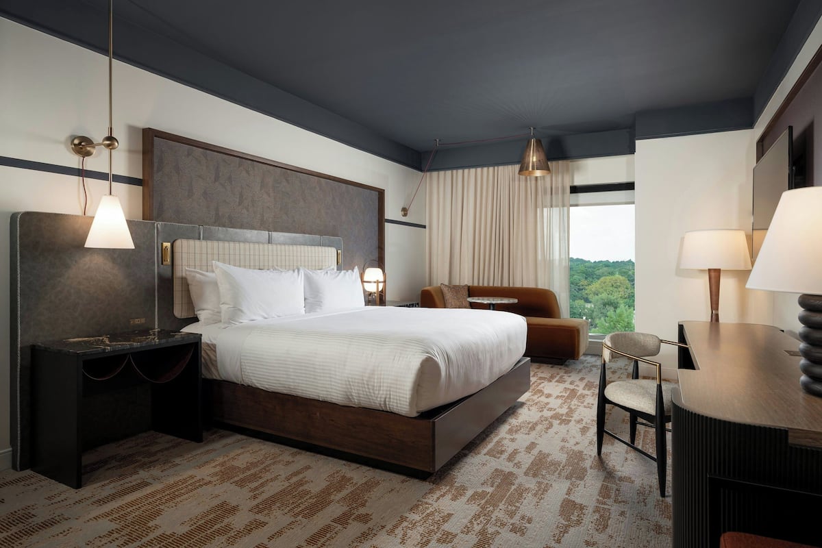 Habitación de hotel moderna con una cama grande, un escritorio, una silla y vistas al exterior.