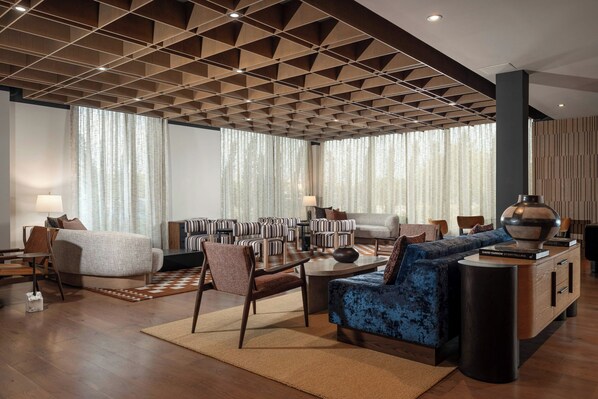 A modern living room with a geometric ceiling, a sofa, a coffee table, and striped chairs. - The Elmore Hotel, DFW Southlake, a Tribute Portfolio Hotel (Southlake)