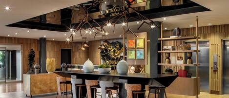 Una cucina moderna con isola centrale, sgabelli da bar, illuminazione a sospensione e soffitto decorato.
