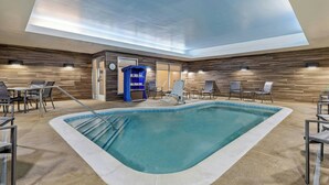A pool area with a ceiling skylight, wooden wall panels, and seating around the pool.