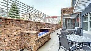 A patio area with a stone wall, a fire feature, and outdoor seating.