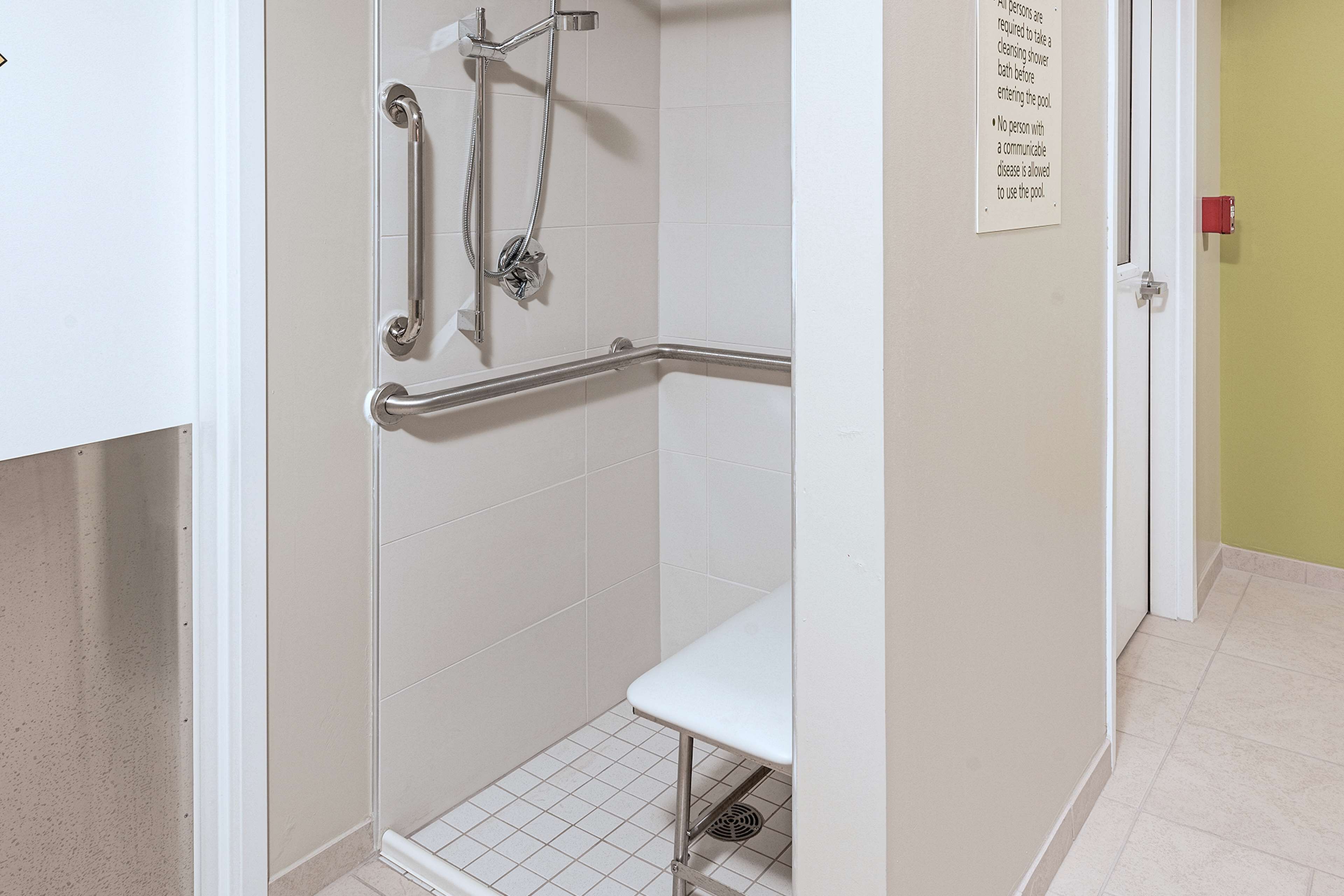 A shower area with grab bars and a bench.