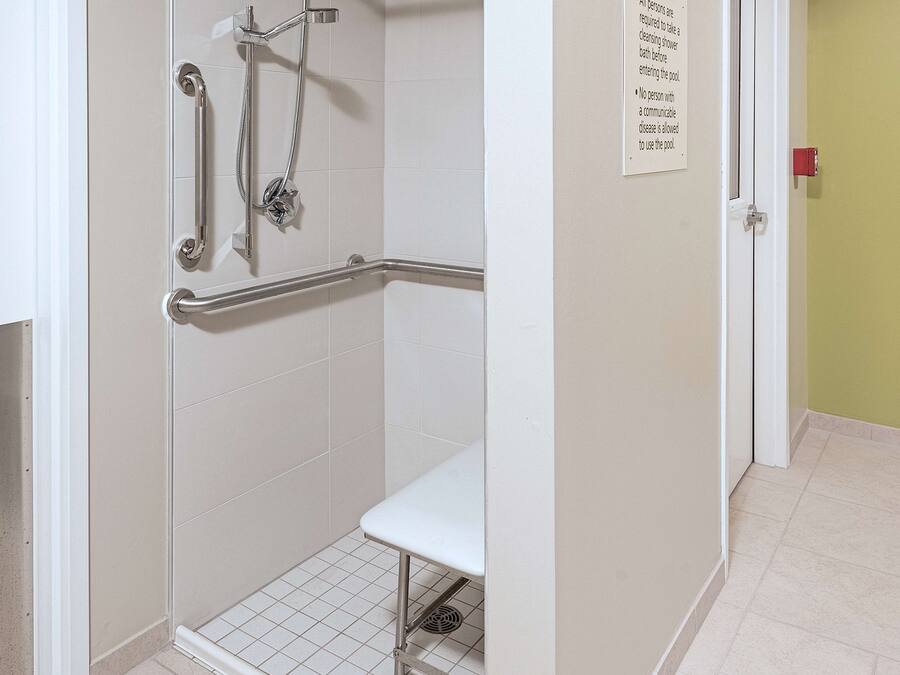 A shower area with grab bars and a bench.