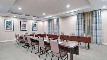 A conference room with a long table, chairs, and framed pictures on the walls.