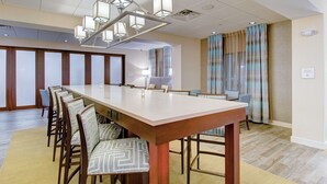 Une salle de conférence avec une longue table, des chaises et un lustre moderne.