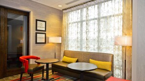 A hotel room with a sofa, two chairs, a small table, and a window with curtains. - Hampton Inn Pulaski (Pulaski)