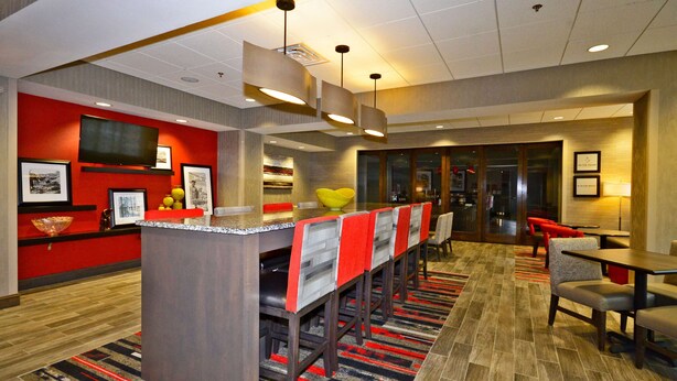 A hotel lobby with a bar area, seating, and a television. - Hampton Inn Pulaski (Pulaski)
