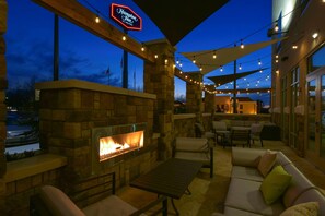 An outdoor patio area with a stone fireplace, seating, and string lights. - Hampton Inn Lumberton (Lumberton)