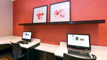 A conference room with two desks, each with a laptop and a chair. There are framed floral artworks on the wall above the desks.