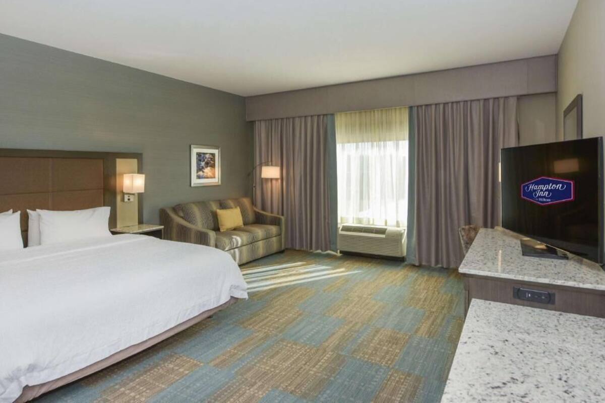 A hotel room with a bed, a sofa, a TV, and a desk.