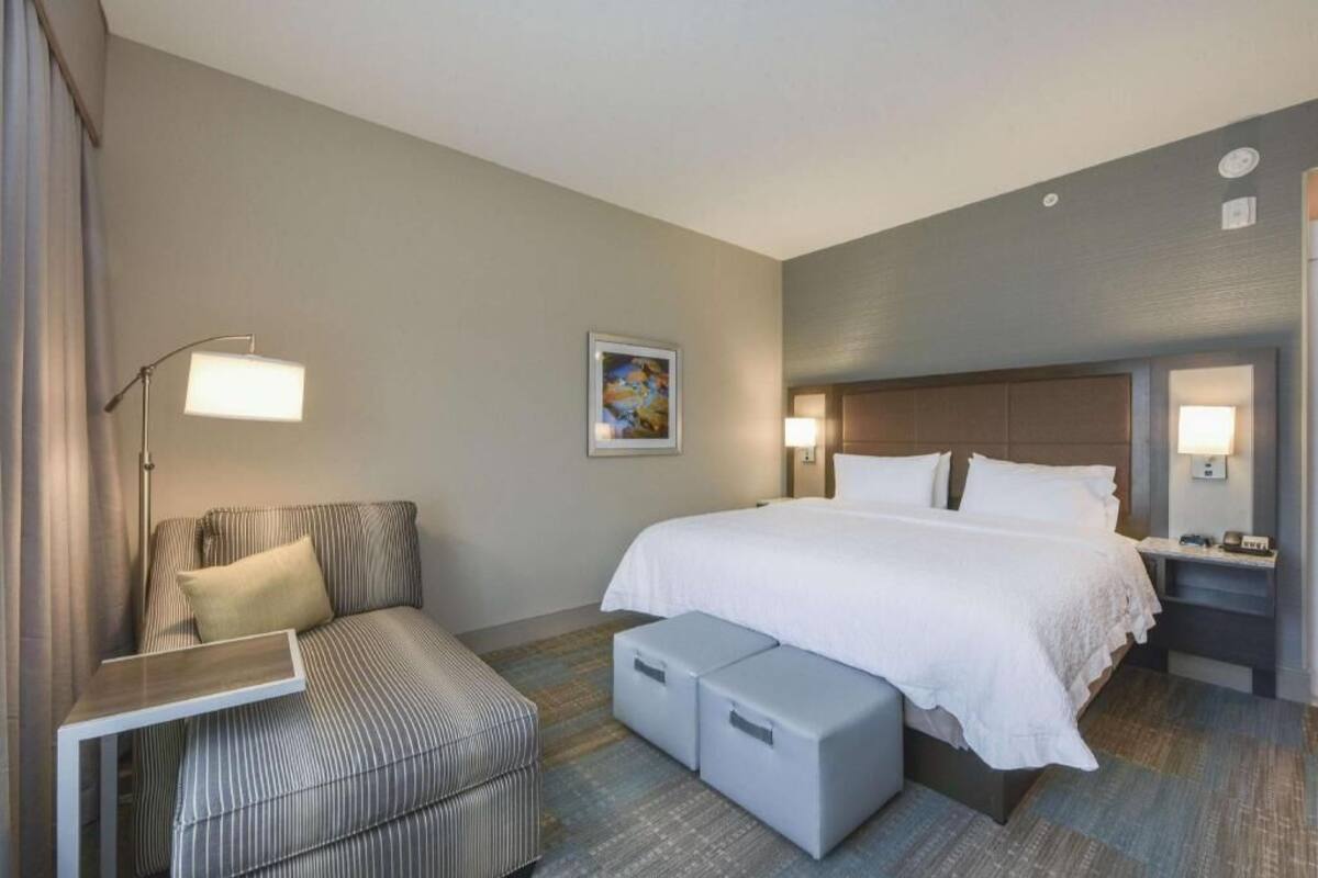 A hotel room with a bed, a sofa, a desk, and a nightstand.