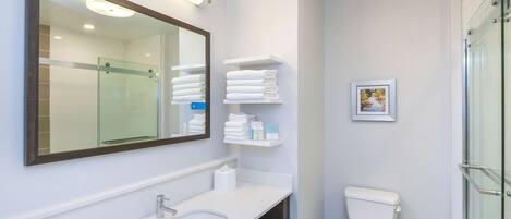 Une salle de bain moderne avec un double vasque, des toilettes et une douche à parois de verre.
