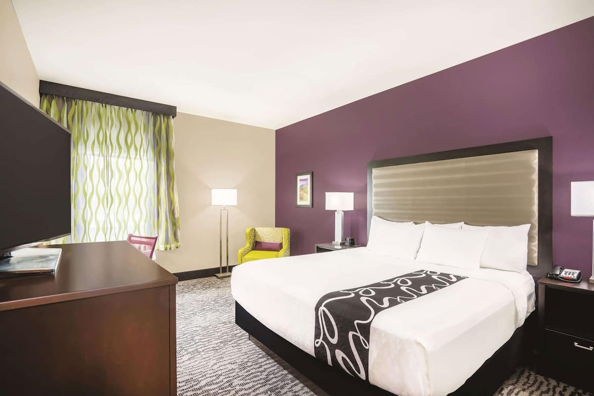 Een hotelkamer met een bed, een bureau, een stoel, een lamp en een telefoon.