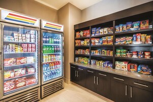 Una sección de aperitivos y bebidas con congeladores refrigerados y estantes llenos de diferentes opciones.