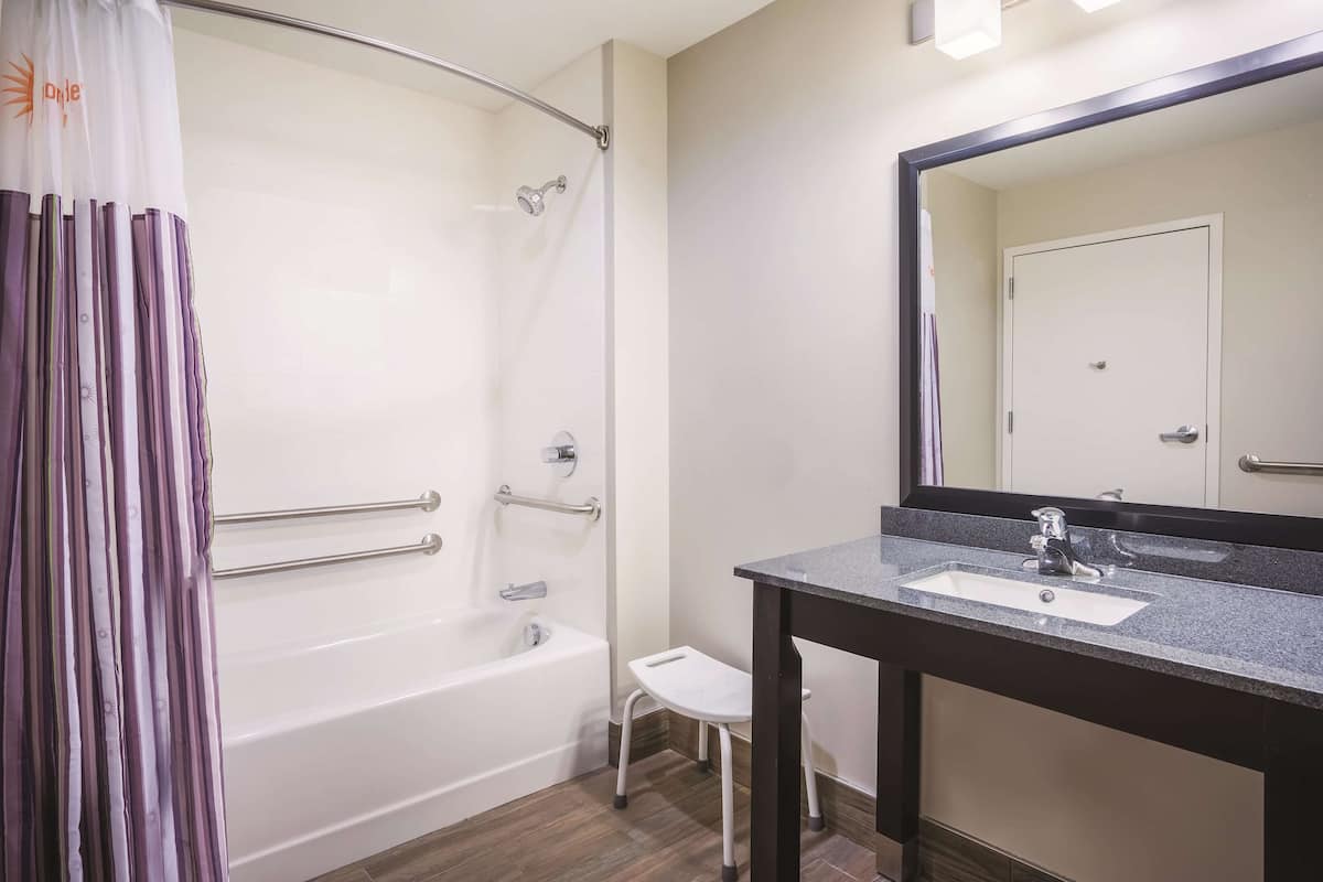 Een badkamer met een douche, een wastafel en een spiegel.
