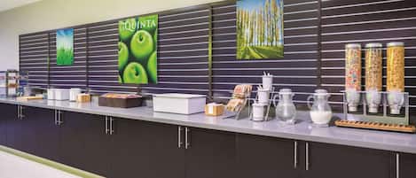 A modern kitchen area with a long counter, various kitchen appliances, and storage cabinets.