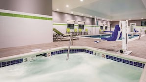 Een zwembadgedeelte van een hotel met een jacuzzi, ligbedden en een glijbaan.