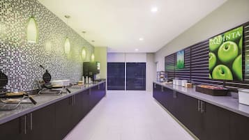 Una cocina moderna con armarios oscuros, salpicadero de azulejos y una encimera amplia con electrodomésticos y una cafetera.