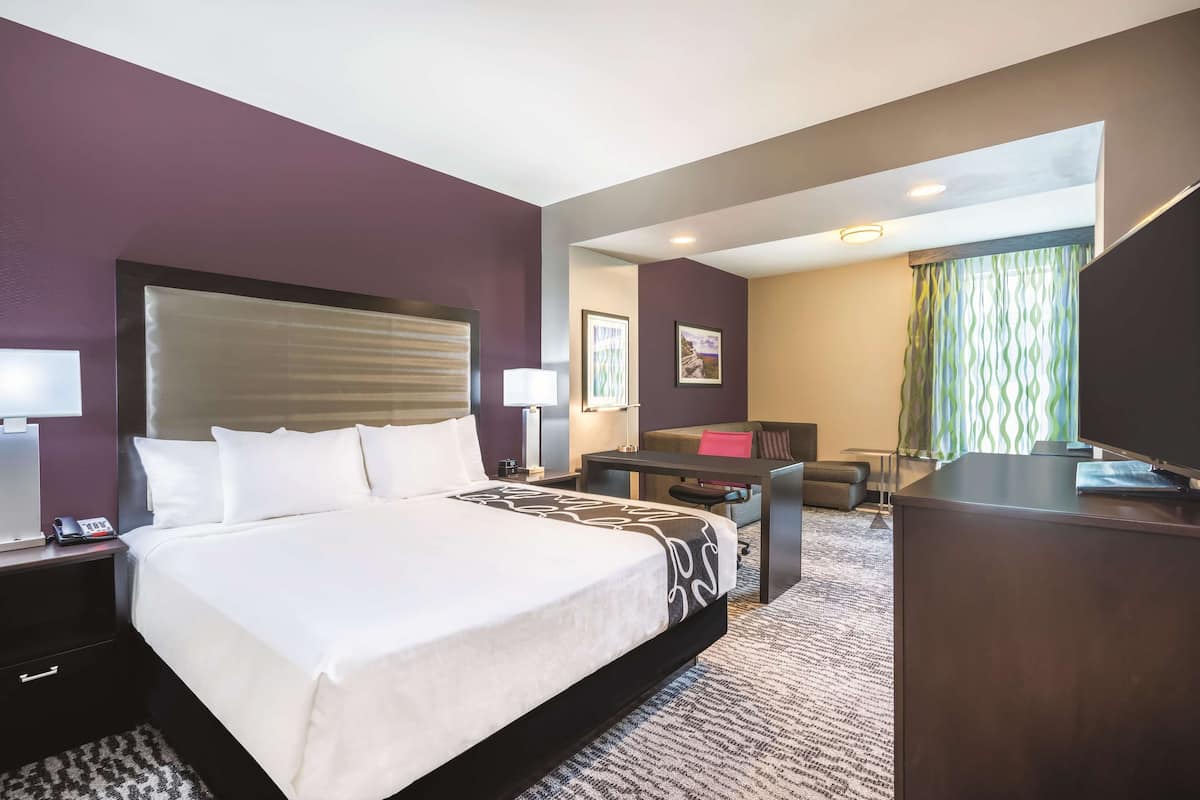 Een hotelkamer met een groot bed, een bureau, een stoel, een bank en een televisie.