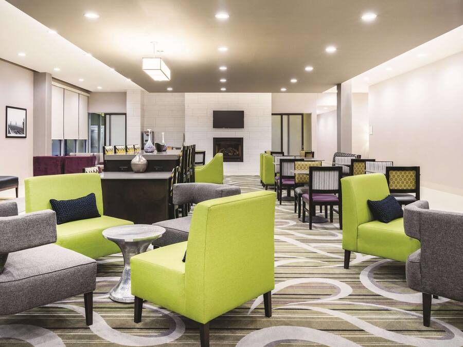 A modern lounge area with seating arrangements, a central table, and a flat-screen TV mounted on the wall.