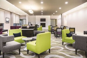 Een moderne lounge met zithoek, een centrale tafel en een flatscreen aan de wand.