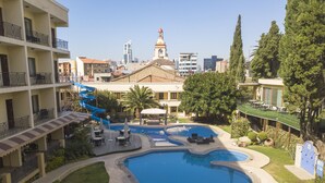 Un hotel con piscina, sillas de descanso y tobogán de agua.