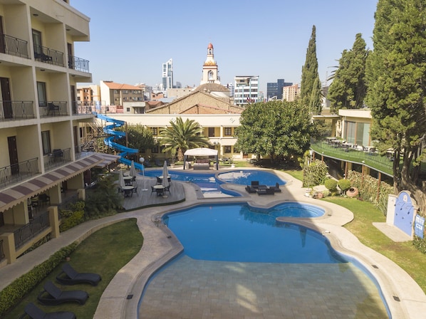 A hotel with a swimming pool, lounge chairs, and a water slide.