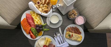 A breakfast buffet with various food items and drinks on a round table.