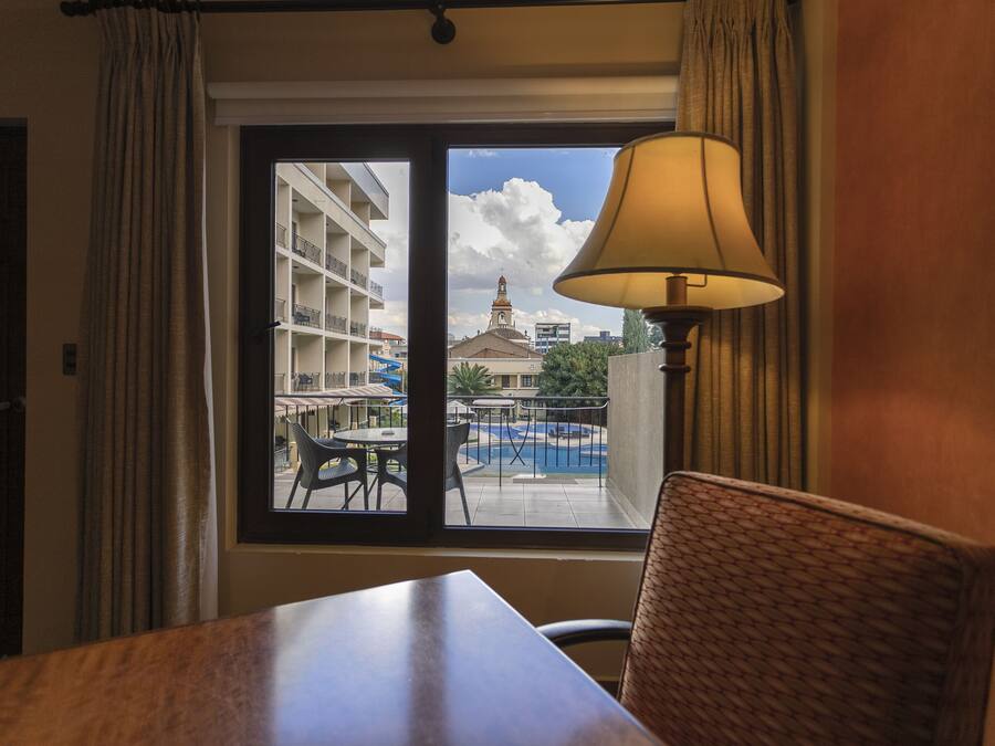 A hotel room with a view of a building with balconies and a pool.