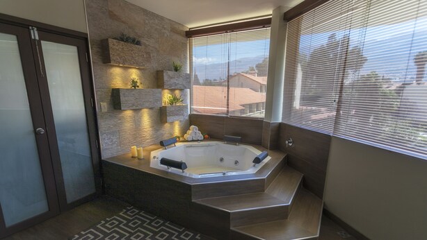 Un baño moderno con una bañera de hidromasaje independiente, estantes empotrados y un tapete estampado.