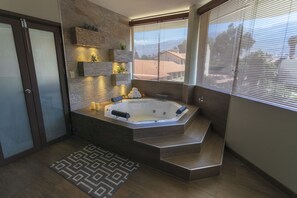 Un baño moderno con una bañera de hidromasaje independiente, estantes empotrados y un tapete estampado.