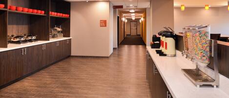 A hotel lobby with a long reception desk, a coffee machine, and a cereal dispenser.