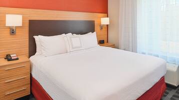 Una habitación de hotel con una cama grande, dos mesitas de noche, un teléfono y una ventana con cortinas.