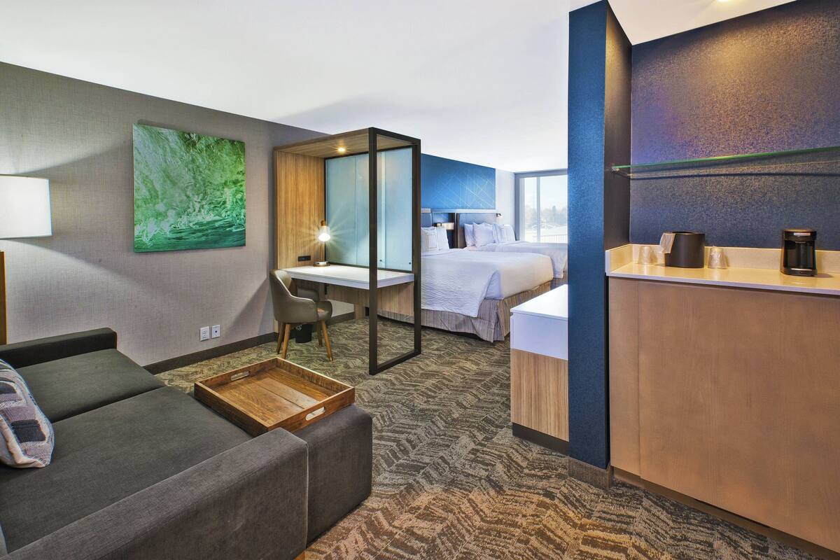 Une chambre d’hôtel équipée d’un canapé, d’un bureau, d’un lit et d’un mini-bar.