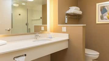 Un baño moderno con un espejo grande, un lavamanos y un inodoro. Hay un perchero sobre el lavamanos y un cuadro en la pared.