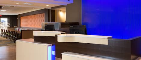 A hotel reception area with a modern design, featuring a reception desk, seating area, and a large blue accent wall.