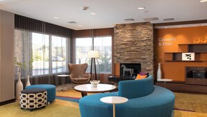 Een moderne hotellobby met een blauwe bank, een ronde salontafel en een accentmuur van steen.