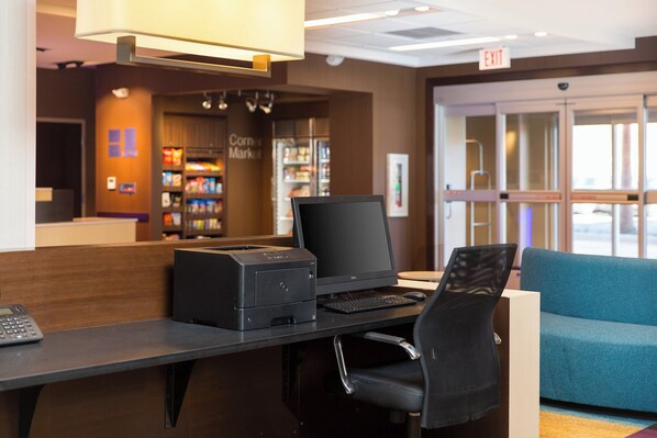 A reception desk with a computer, printer, and a seating area with a blue couch.