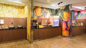 Een receptiegedeelte met een houten receptiebalie, een digitaal scherm en een wanddecoratie met fruitmotieven.