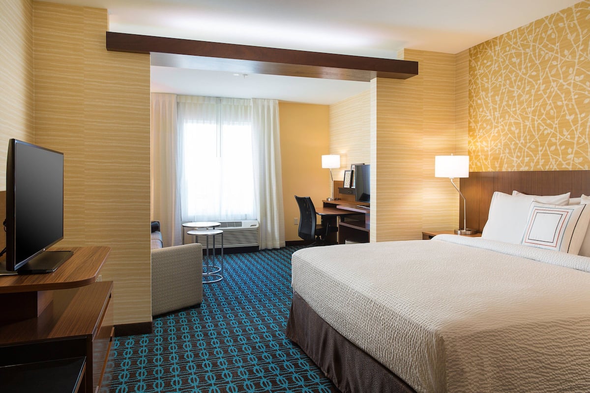 Een hotelkamer met een groot bed, een bureau met een computer, een televisie en een stoel.