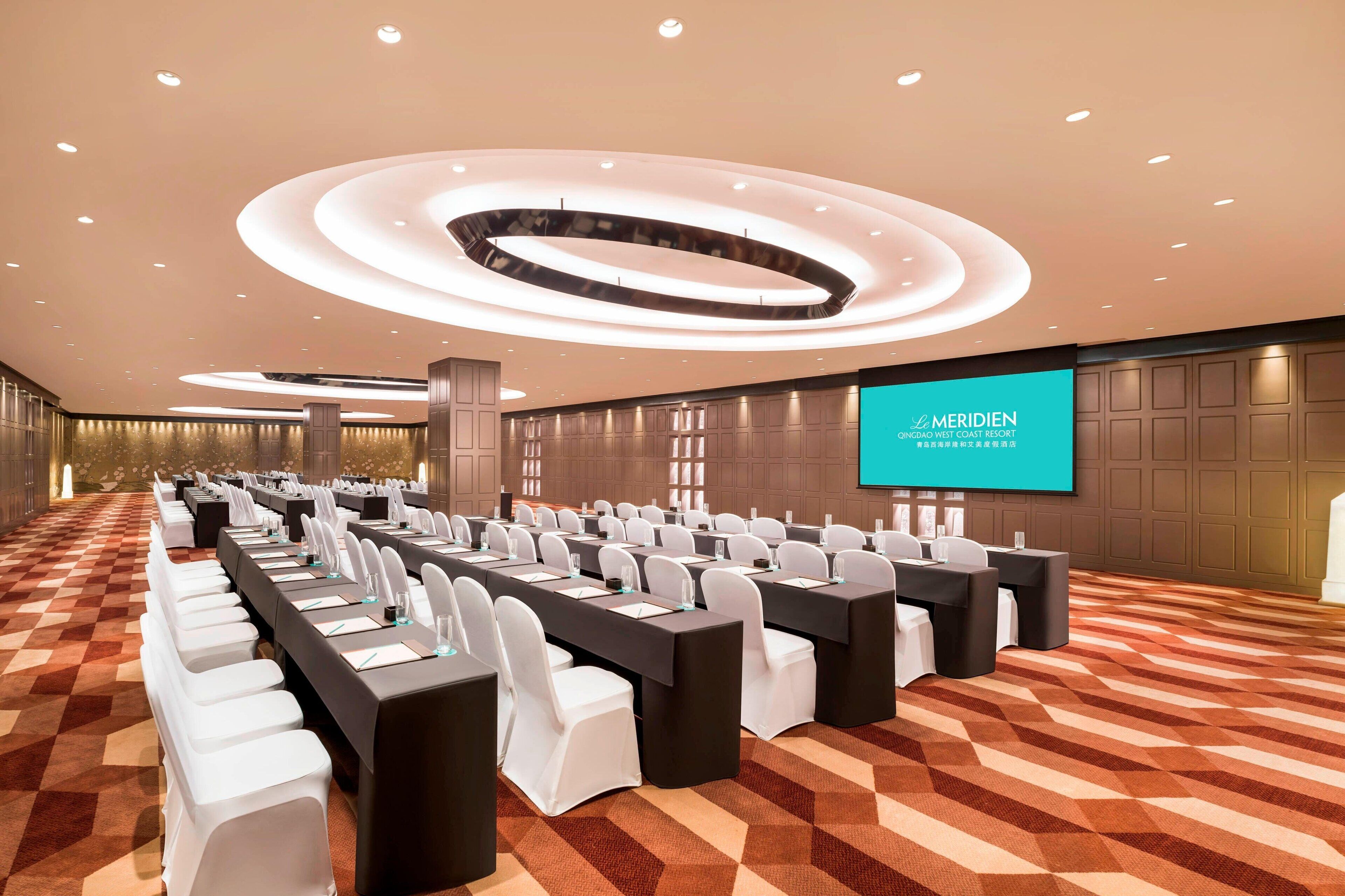 A conference room with a long table, white chairs, and a large screen displaying 'MERIDEN'.