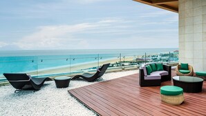 Una terraza con vistas a la playa, amueblada con sillones y sofás.