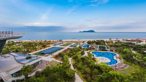 Un resort con una amplia piscina, jardines ajardinados y vistas al mar.