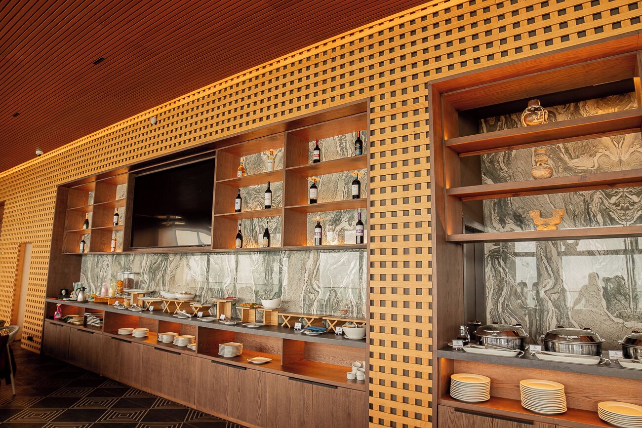 A modern kitchen with marble countertops, wooden shelves, and a variety of kitchenware and appliances.