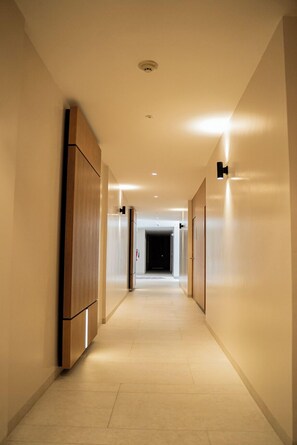 Un corredor moderno de hotel con paneles de madera en las paredes, iluminación empotrada y suelo de baldosas.
