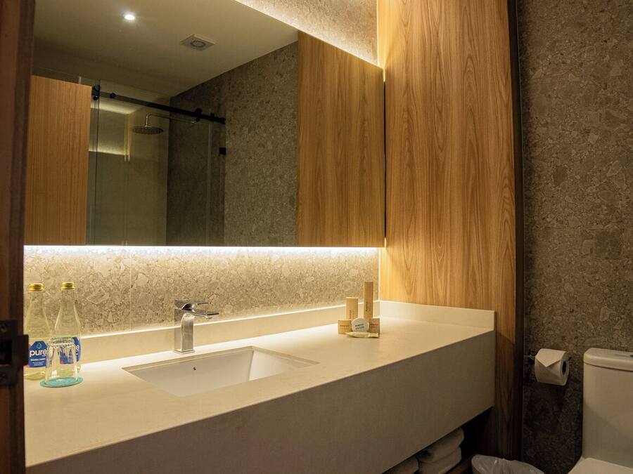 A modern bathroom with a large mirror, a white sink, and a shower.