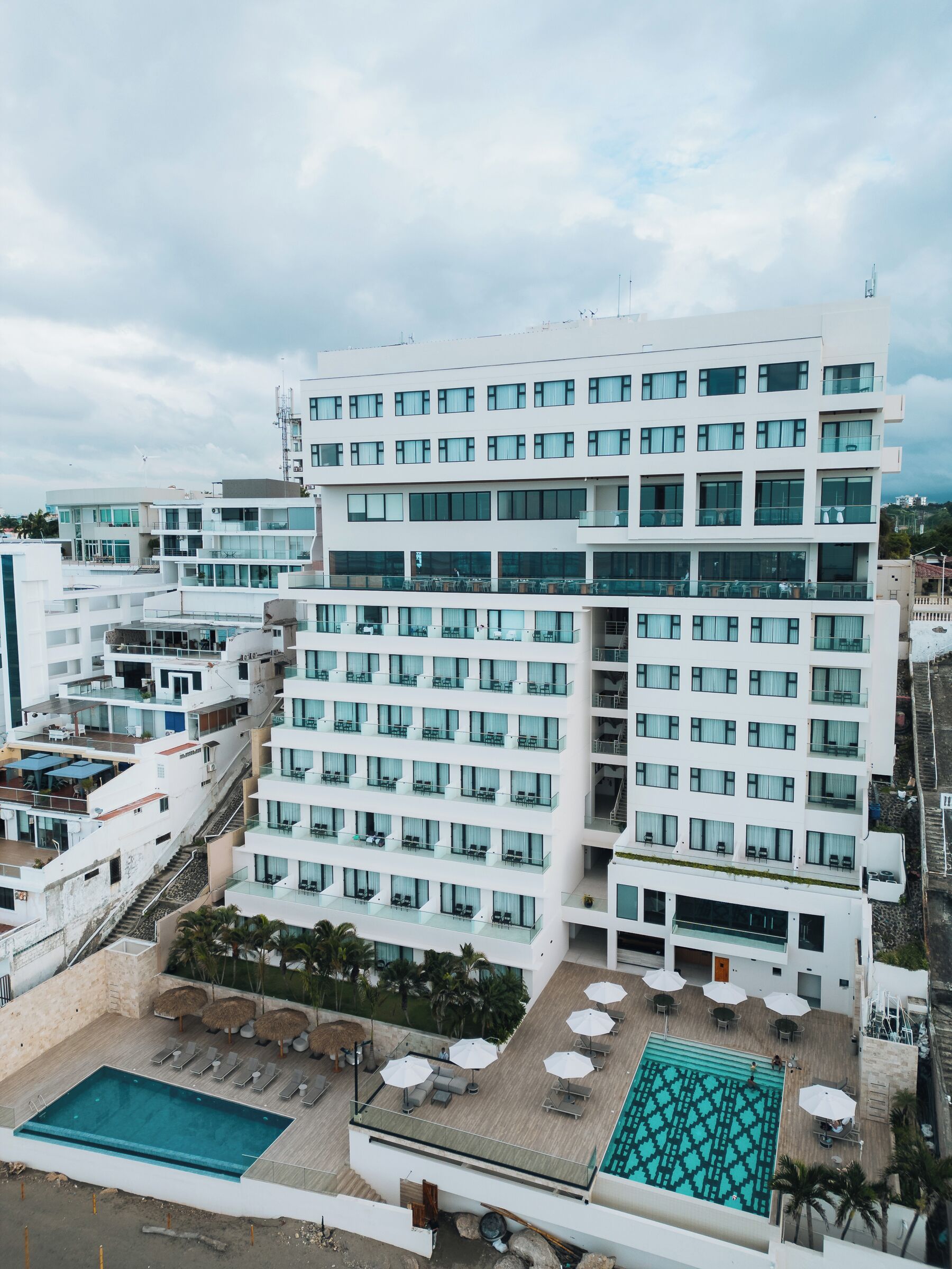 A multi-story hotel with a rooftop pool area, including sun loungers and umbrellas.